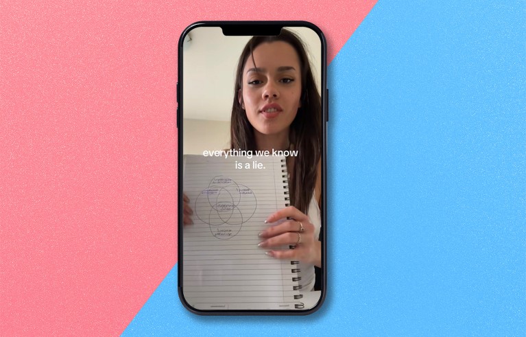 A smart phone displays a still from a vertical TikTok video titled "Everything we know is a lie" with a young woman holding up a venn diagram drawn on a ringbound notepad.