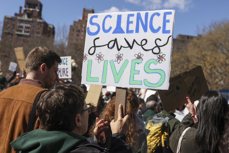 People hold signs and protest the Trump administration's cuts to federal scientific funding during a 'Stand Up for Science' rally, 2025.