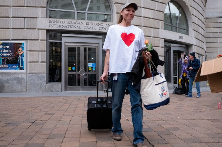 A woman leaves the Ronald Reagan Building in tears carrying bags and pulling a suitcase.