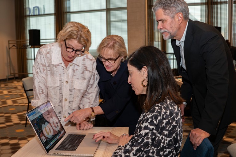 Three women and a man looking at a computer screen.