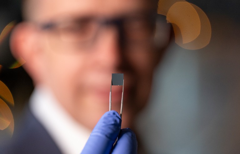 Чип који у пинцети држи човек који је ван фокуса у позадини.