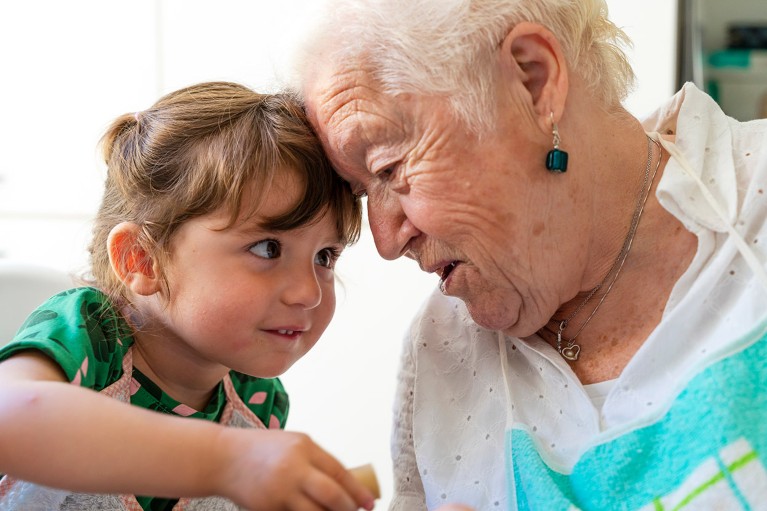 A grandmother and her granddaughter resting their heads together.