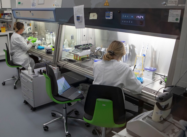 Two researchers wearing lab coats and gloves at work in a laboratory.