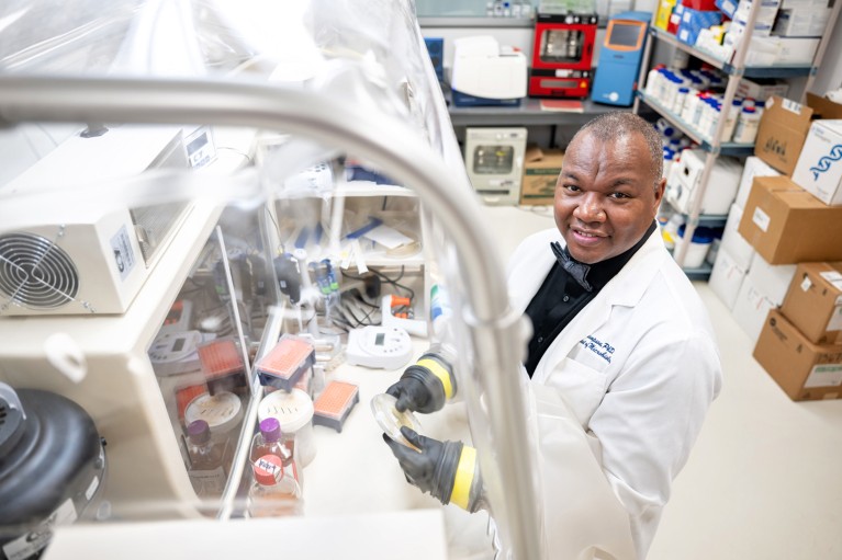 Карл Томпсон, професор на Универзитету Хауард, позира за портрет док користи претинац за рукавице у лабораторији
