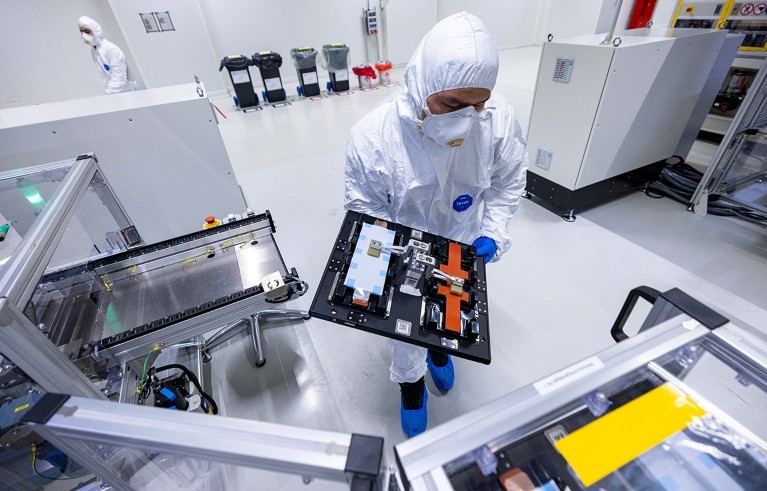 An employee holds finished cell stacks at a production line inside a cleanroom at the PowerCo SE battery, Germany.