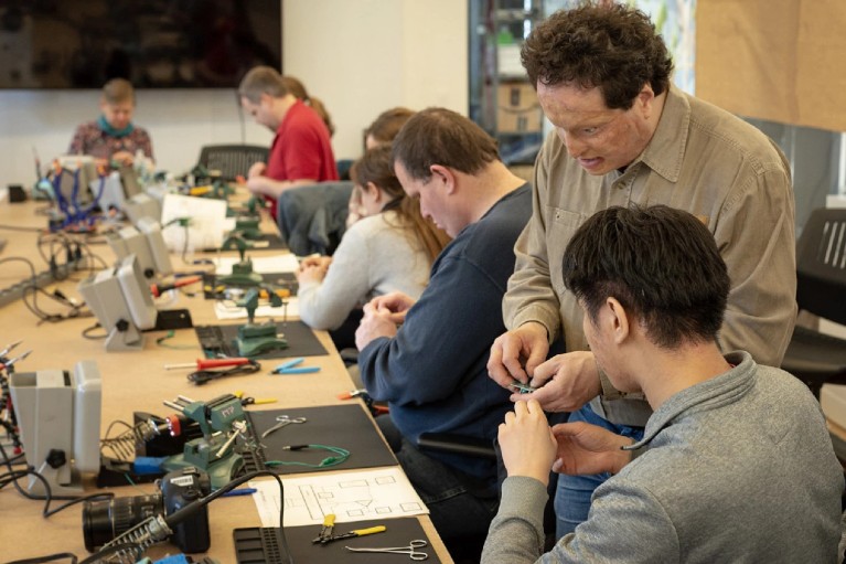 Josh Miele teaching hands-on blind soldering techniques at a workshop with students.