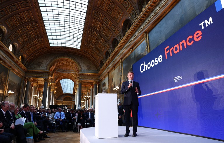 Француски председник Емануел Макрон држи микрофон док говори на сцени пред публиком "Изаберите Самит у Француској".