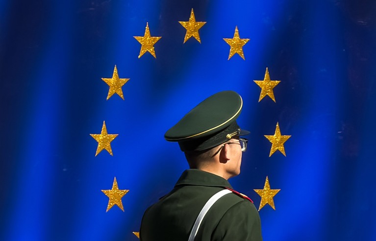 A Chinese People's Armed Police officer pictured patrolling in front of a large European Union flag.