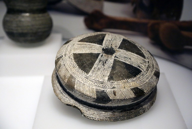 A ornately patterned piece of Bell-Beaker pottery on display in a museum.