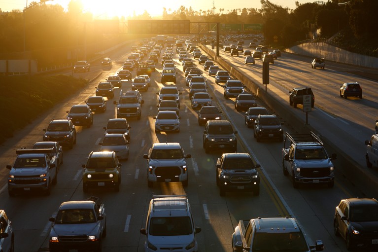Много стационарних саобраћајних трака на међудржавној аутопуту у Калифорнији са заласком сунца у даљини