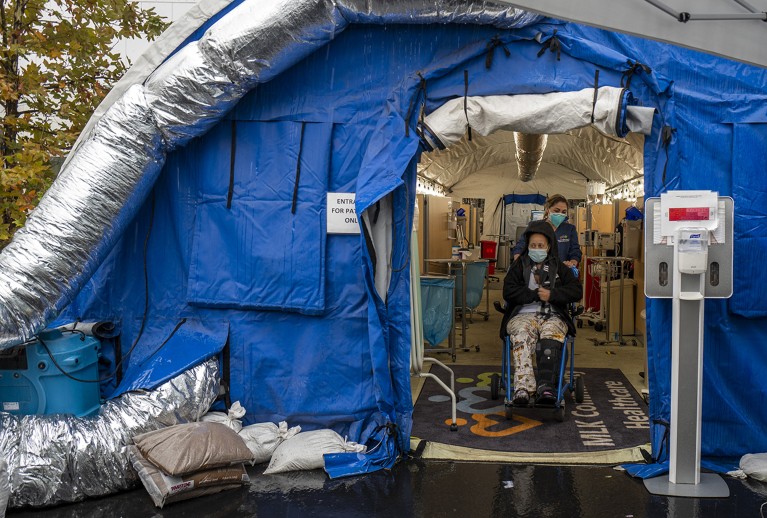 Двоје људи са маскама за лице у плавом шатору, из којег излазе луле сребрне боје.