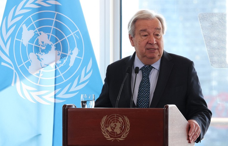 United Nations Secretary General Antonio Guterres delivers a speech at a podium beside a flag bearing the United Nations emblem.
