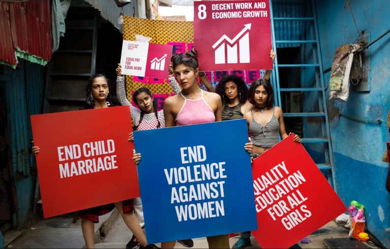 Women holding red and blue placards saying 'end child marriage', 'end violence against women' and 'quality education for all girls'.e among the United Nations' Global Goals for Sustainable Development.