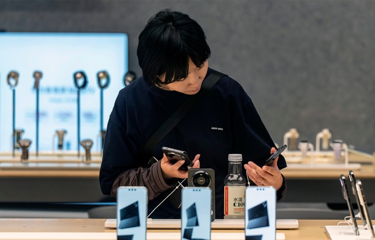 A young customer with black hair and black jumper looks at smartphones at a Huawei Technologies Co. store in Shenzhen, China.
