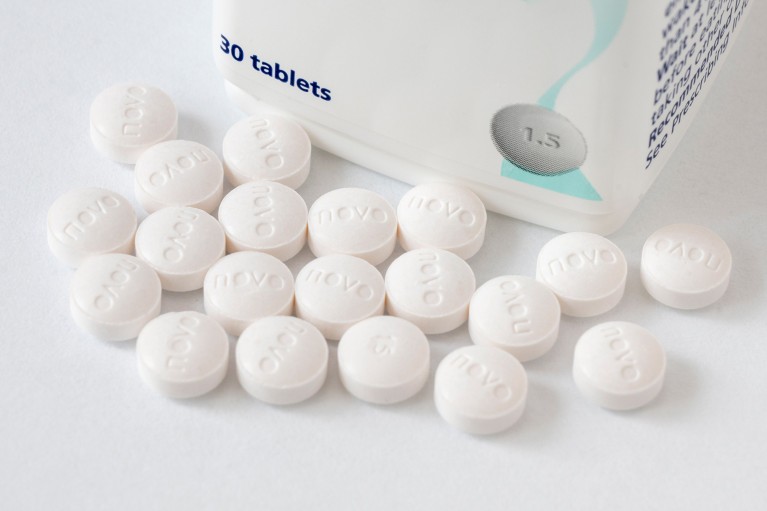 A close-up of round white Wegovy semaglutide tablets pictured next to their bottle on a white background