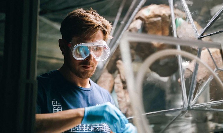 Ryan Gosling in a movie still from Project Hail Mary wearing safety goggles while working in a lab.