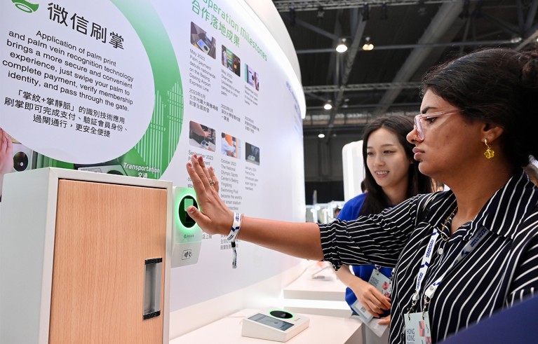 Woman holds her hand in front of a palm scanner at a technology exhibition.