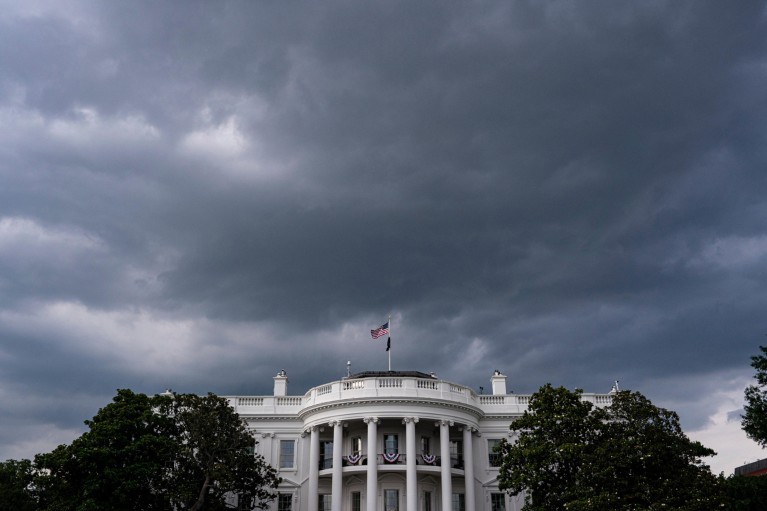Storm clouds are seen over the White House with the U.S. flag flying above the building