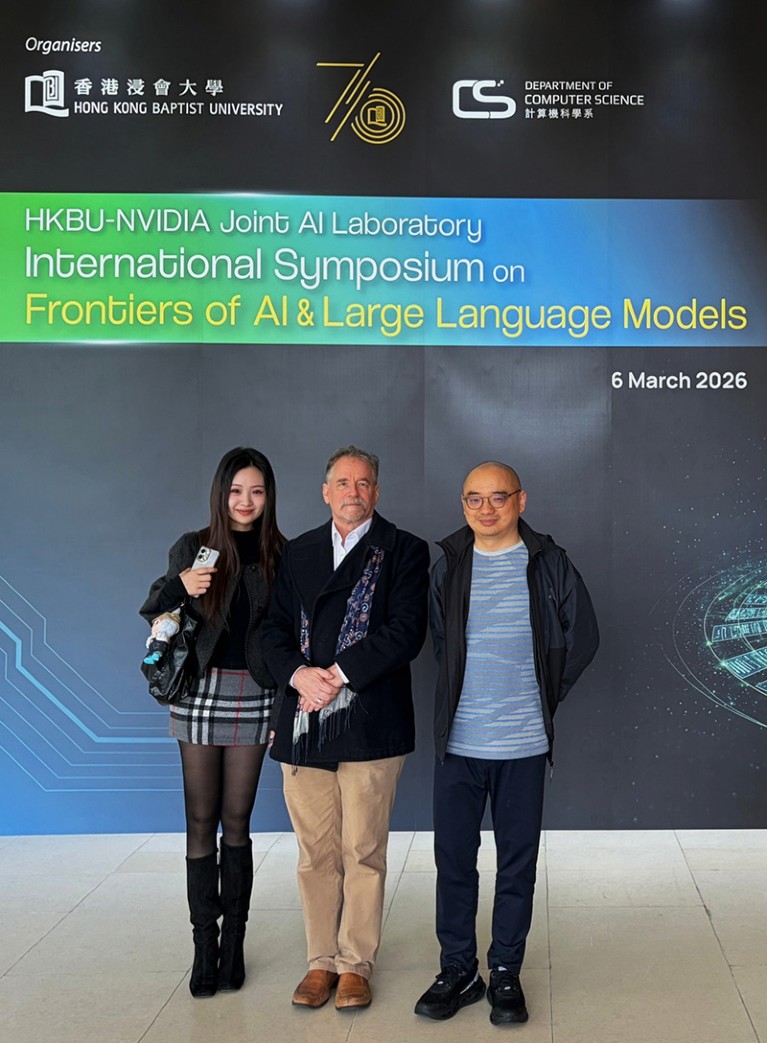Miss Yu Ruobin, Professor Stuart Christie, and Dr. Simon H. Wang stand in front of a banner that reads, “HKBU-NVIDIA Joint AI Laboratory International Symposium on Frontiers of AI & Large Language Models, 6 March 2026”