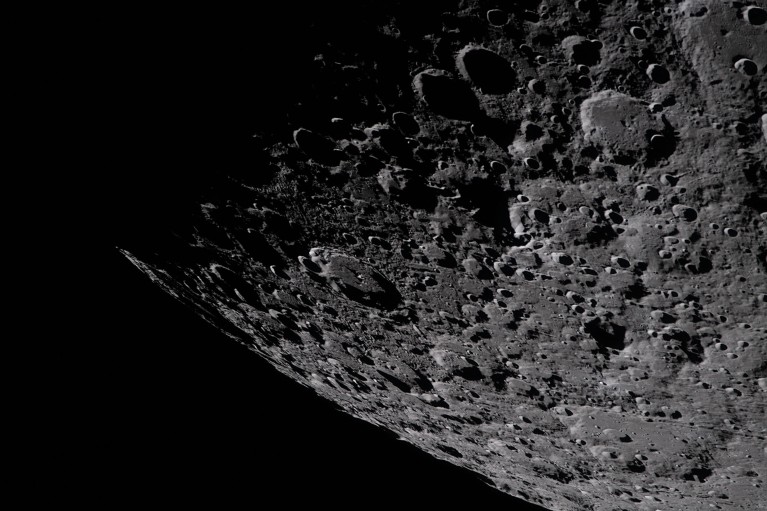 The heavily cratered terrain of the Moon as a shadow moves across it from the top left.