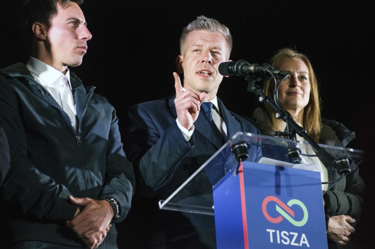 Peter Magyar gives a speech flanked by his supporters.