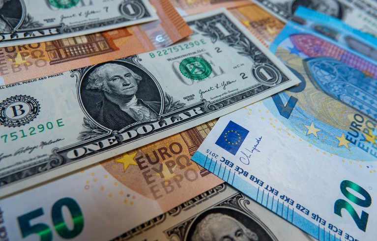 Close-up of US dollar bills and euro banknotes scattered together.
