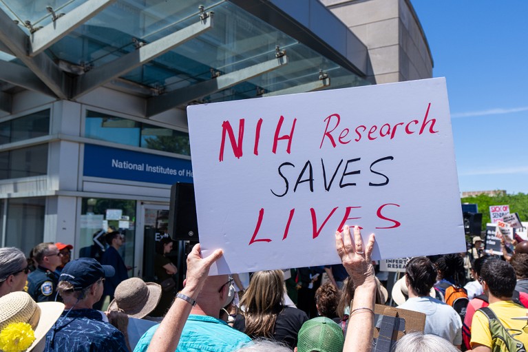 Activists hold signs of support during a rally at the National Institutes of Health outside their offices in the U.S.