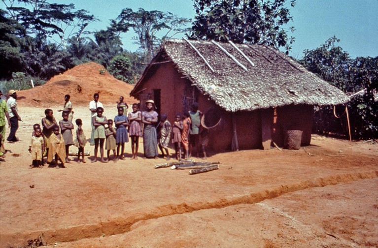 Historic colour image from the 1976 ebola outbreak, showing residents stood outside of a thatched building in a rural village in Zaire.