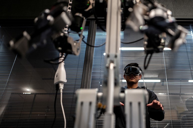 An engineer uses a VR headset to operate a robotic arm.