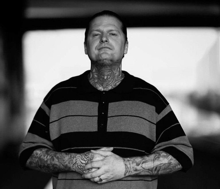 Black and white photo of Ryan Rising standing with his hands clasped in front of him.