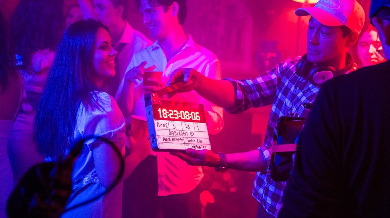 Woman smiles while a clapperboard is held up during the filming of Gaslight.
