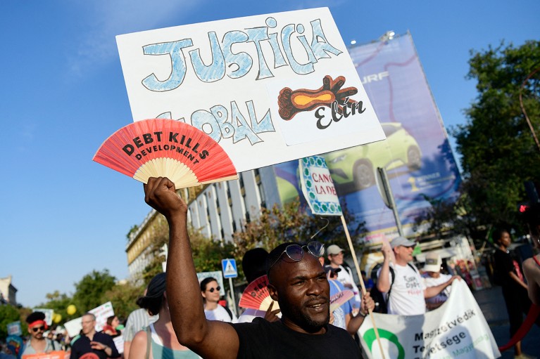A man holds a sign reading "Global justice" during a protest march in Spain to demand UN-led solutions on the sovereign debt crisis and global wealth inequality.