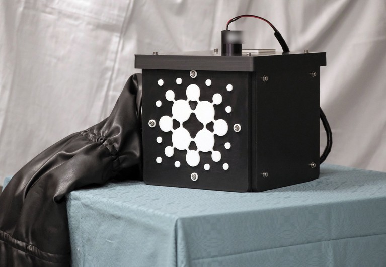 A black box with a white design on the side and a lid through which electrical wires enter.