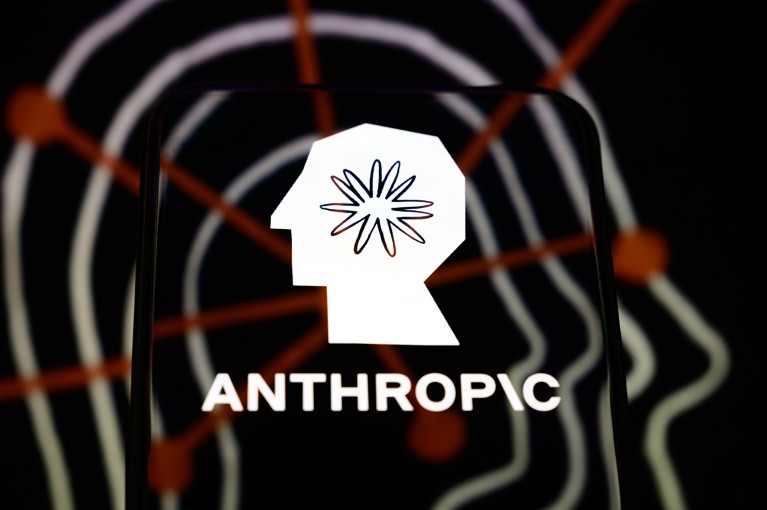 The Anthropic logo is displayed on a smartphone screen, placed on a reflective surface onto which a company branding illustration is projected.