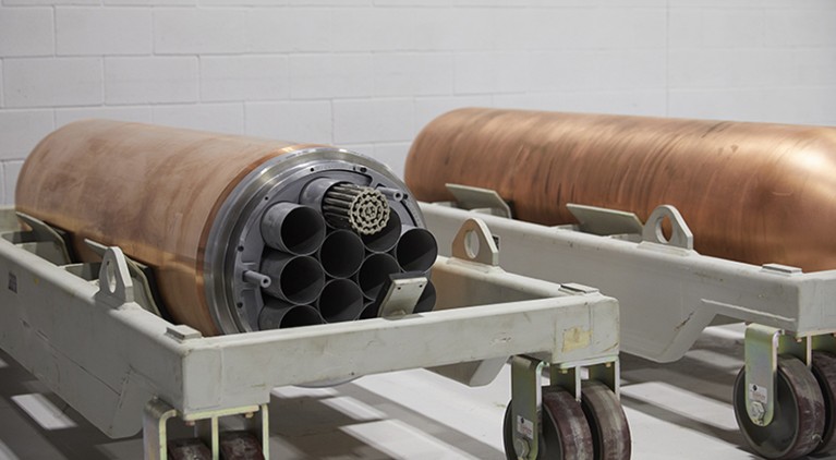 Two cylindrical copper fuel containers displayed in a white room.
