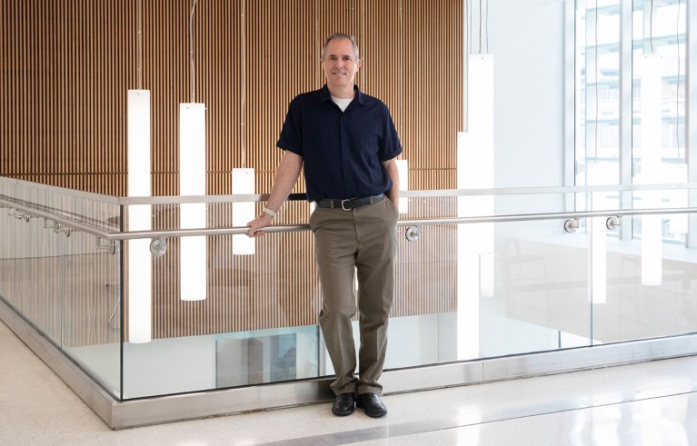 Posed portrait of Brian Nosek leaning against a glass balustrade in a well-lit atrium.