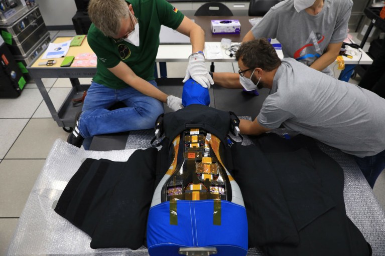 Three technicians assemble the AstroRad vest on a mannequin’s torso.