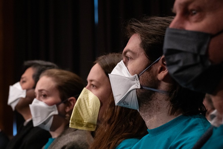 A row of people wearing COVID-style protective face masks.