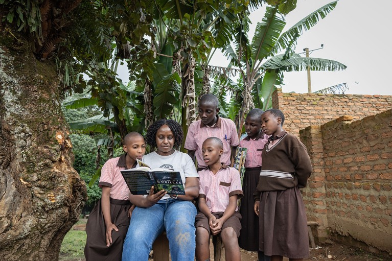 Gladys Kalema-Zikusoka reads a book about gorillas to children outside a school in Uganda.