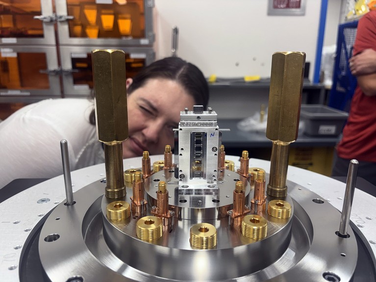 A researcher inspects a target containing a sample, consisting of metallic tube-like structures mounted within a circular holder, prior to its insertion into the Z Machine.
