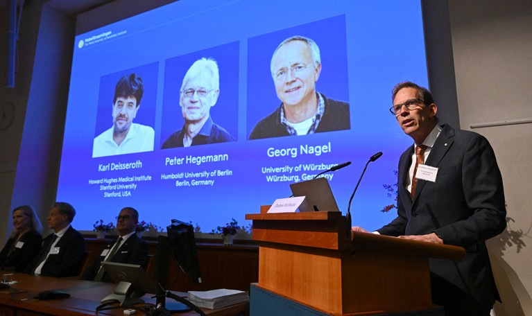 Nobel Committee Secretary General Thomas Perlmann speaks to the media in front of a screen displaying the names and photos of the 2026 winners of the Nobel prize in Medicine.
