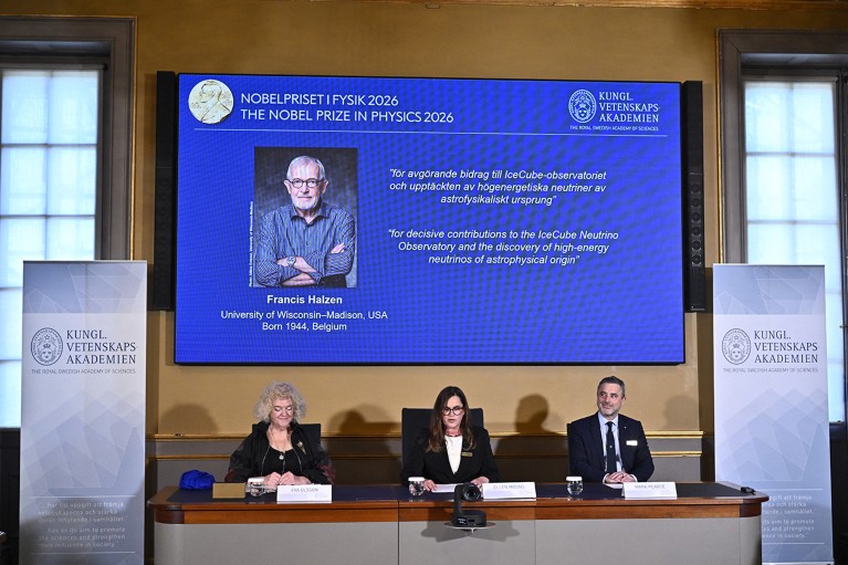 Three Nobel prize panel members sit in front of a screen anouncing Francis Halzen as the winner of the 2026 Nobel prize in physics.