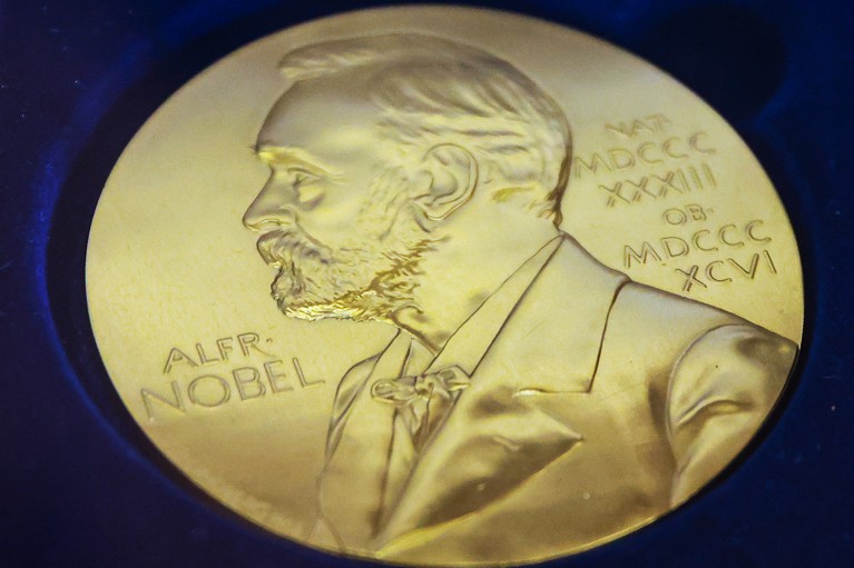 Close-up of a Nobel prize medal on a blue background.