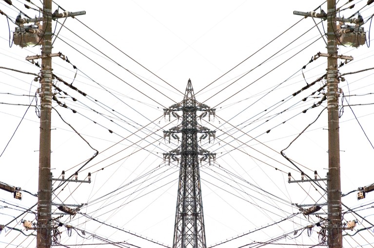 Multiple high-voltage power lines connecting to each other, seen from underneath.