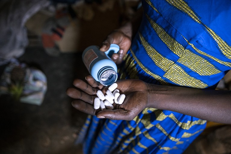 A mother tips the remaining white Antiretroviral pills from a container into the palm of her hand at her home. Her son who was HIV positive died due to lack of Antiretroviral drugs following the USAID funding cut.