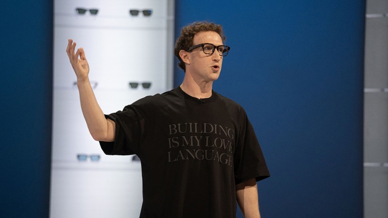 Mark Zuckerberg speaking onstage, wearing glasses and a T-shirt that reads 'Building is my love language'.