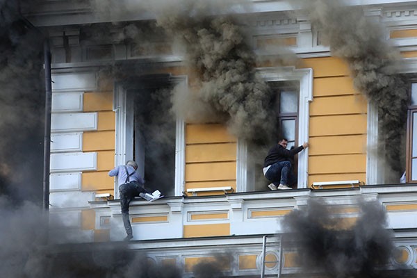 Two men cling to window ledges as they try to escape from the burning National Academy of Sciences building in Kyiv, Ukraine, after it was struck by a Russian drone.