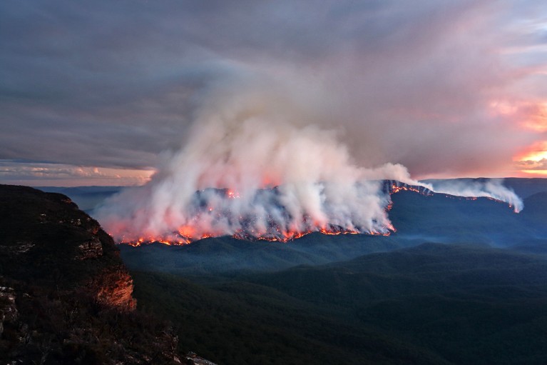 View at dusk showing a bushfire engulfing the forested hillside of Mount Solitary in Australia.