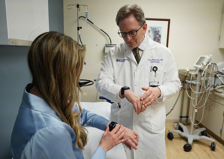 Two people in a clinic looking at smart watches on their wrists. Person on the right is Rod Passman.