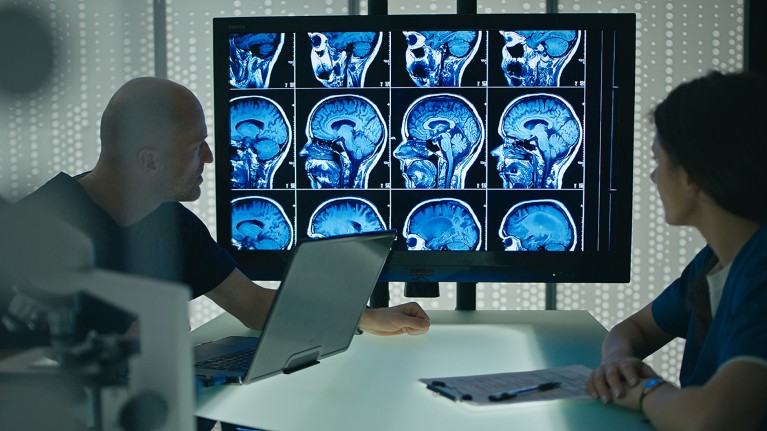 Two researchers review brain structure and brain waves on a screen in a neurological laboratory,